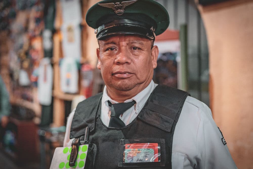 A uniformed security guard with an ID card clipped to his vest