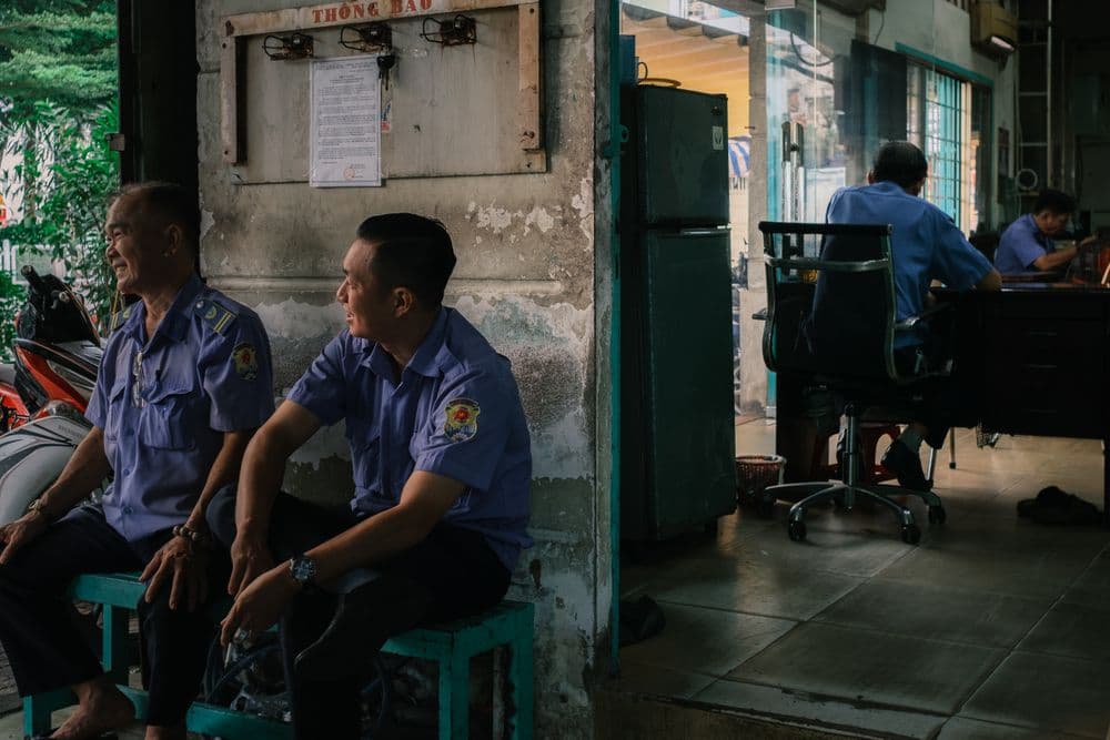 Uniformed security officers in their site office, one working at a desk