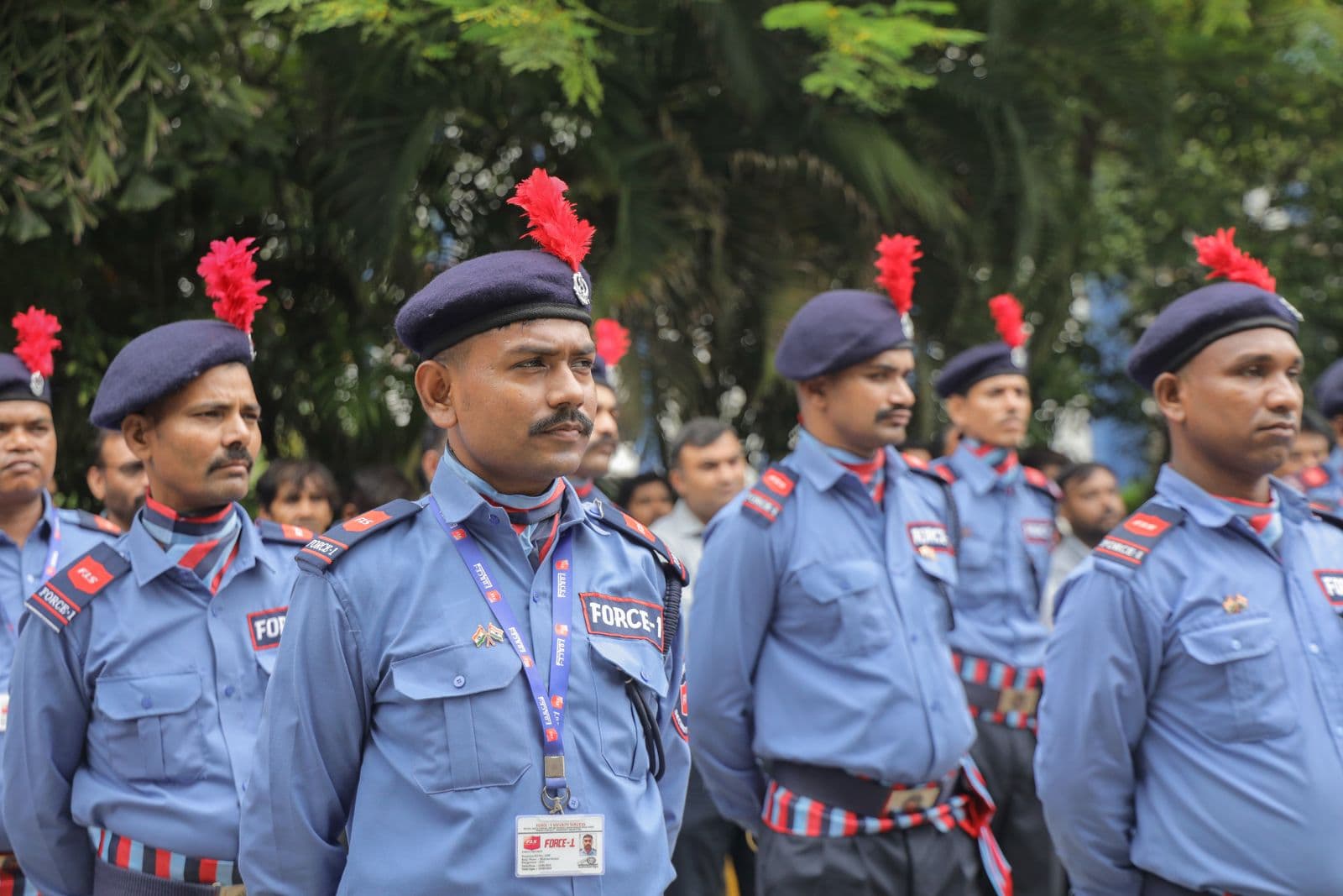 A team of uniformed private security guards with ID badges standing in line outdoors