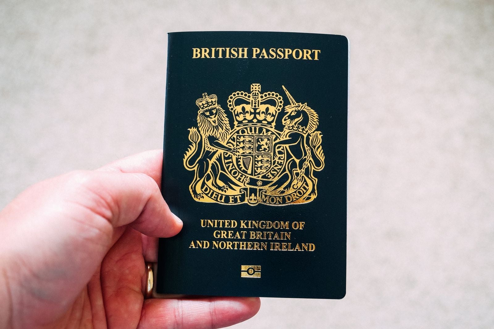 A hand holds up a dark blue British passport