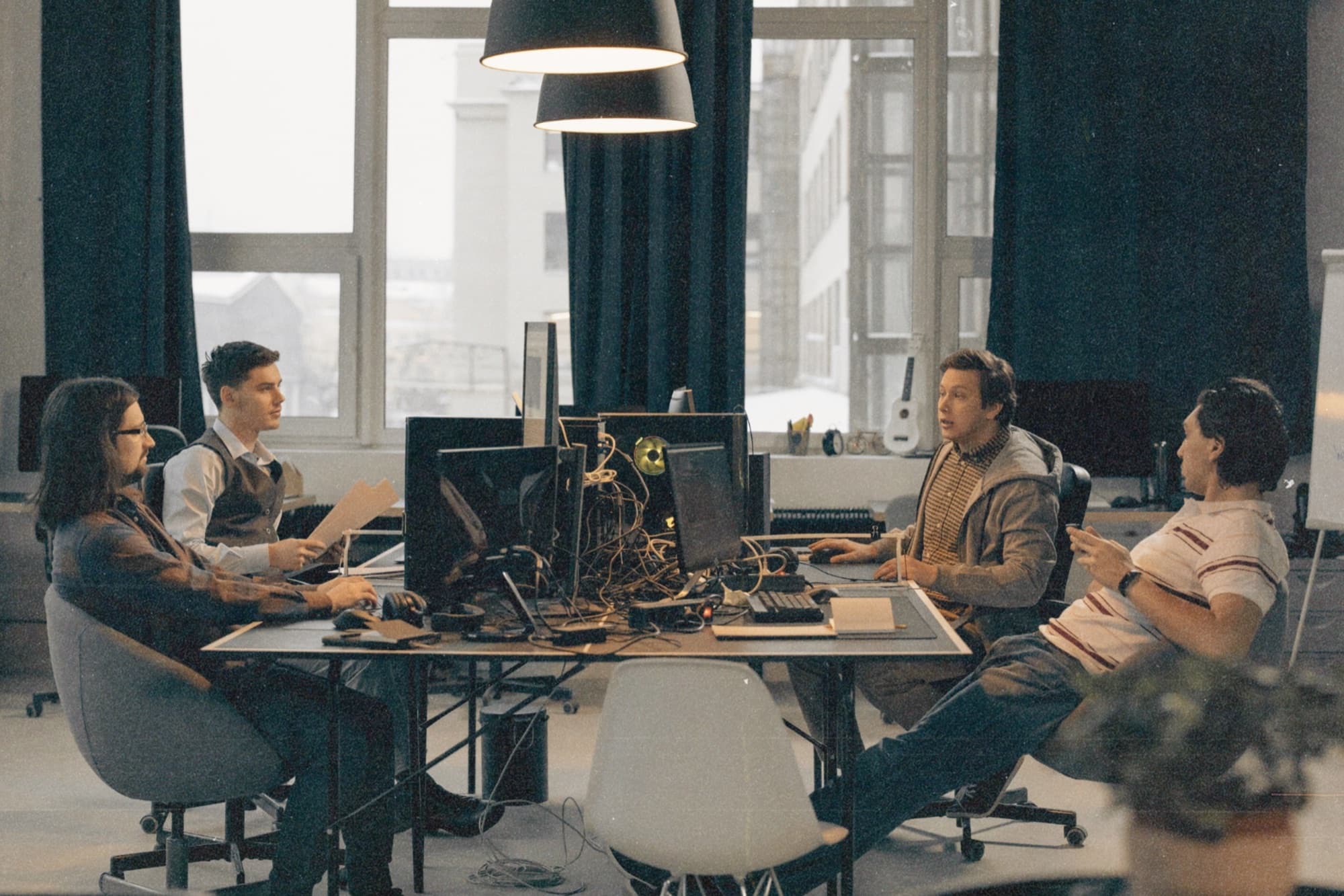 A recruitment team talking through their week around a shared desk
