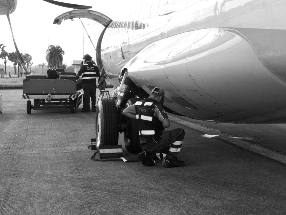 Two maintenance technicians work on an aircraft’s main landing gear wheel on the ramp