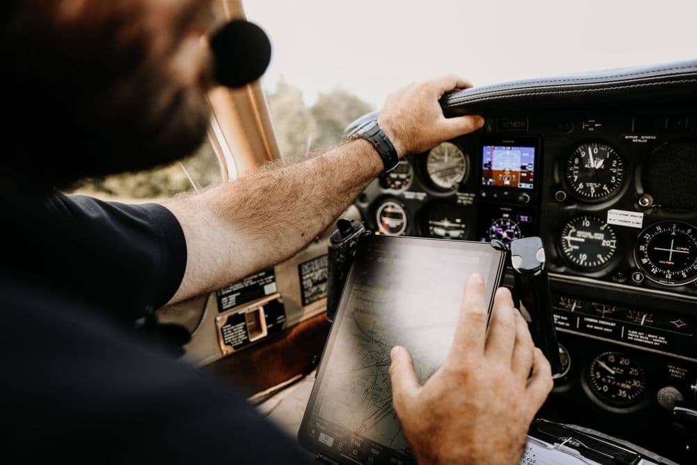A pilot holds a tablet beside the instrument panel of a light aircraft