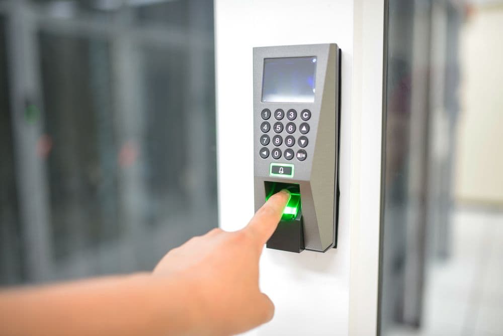 A finger pressed to a fingerprint reader on a secure door
