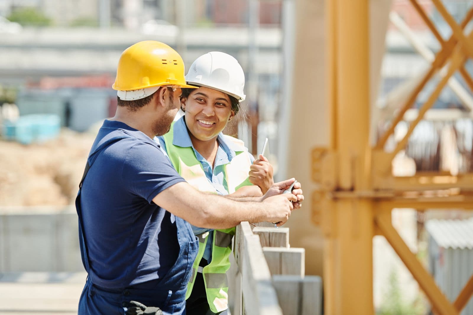 Two construction workers in hard hats sharing a smile on site