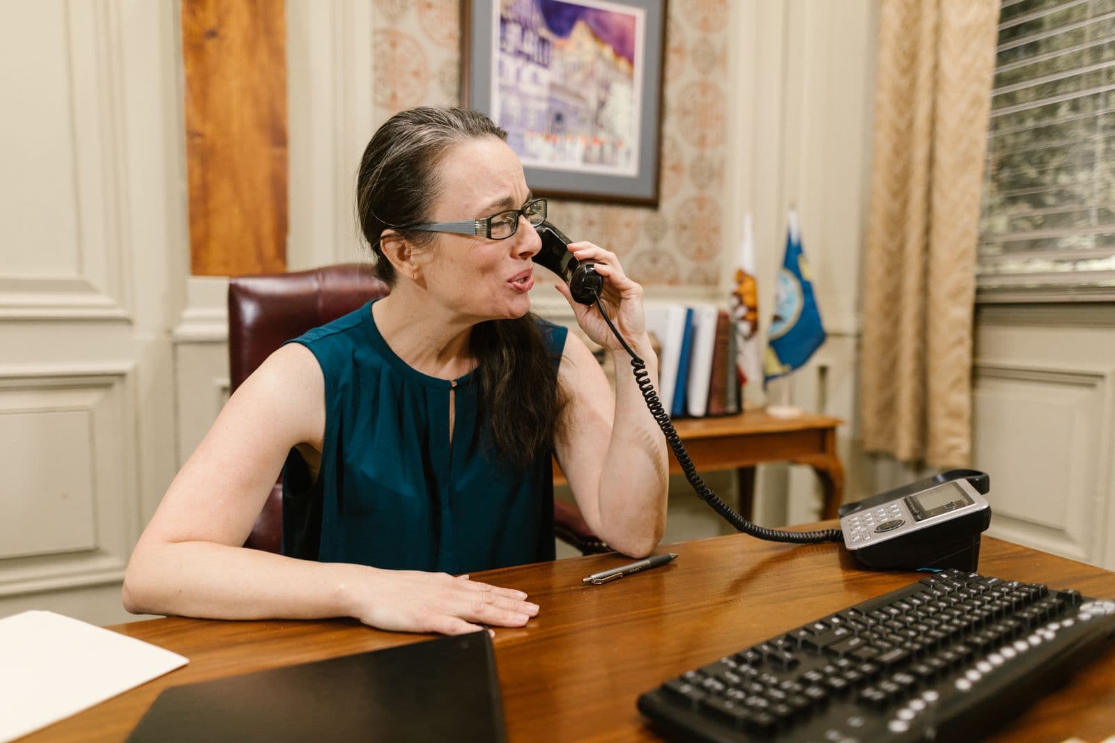 An administrator on the desk phone in a wood-paneled school office