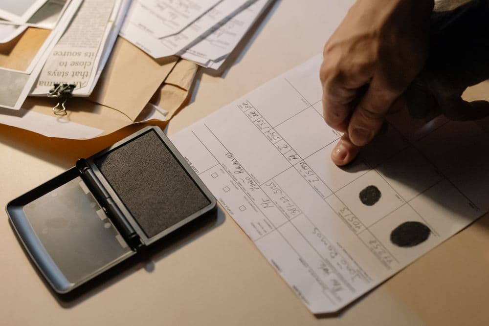 A fingerprint card being inked beside an ink pad and a pile of papers