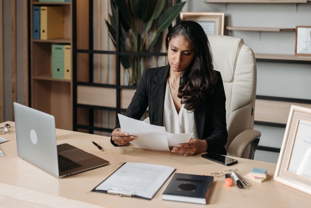 A credentialing specialist reviewing a document at her desk