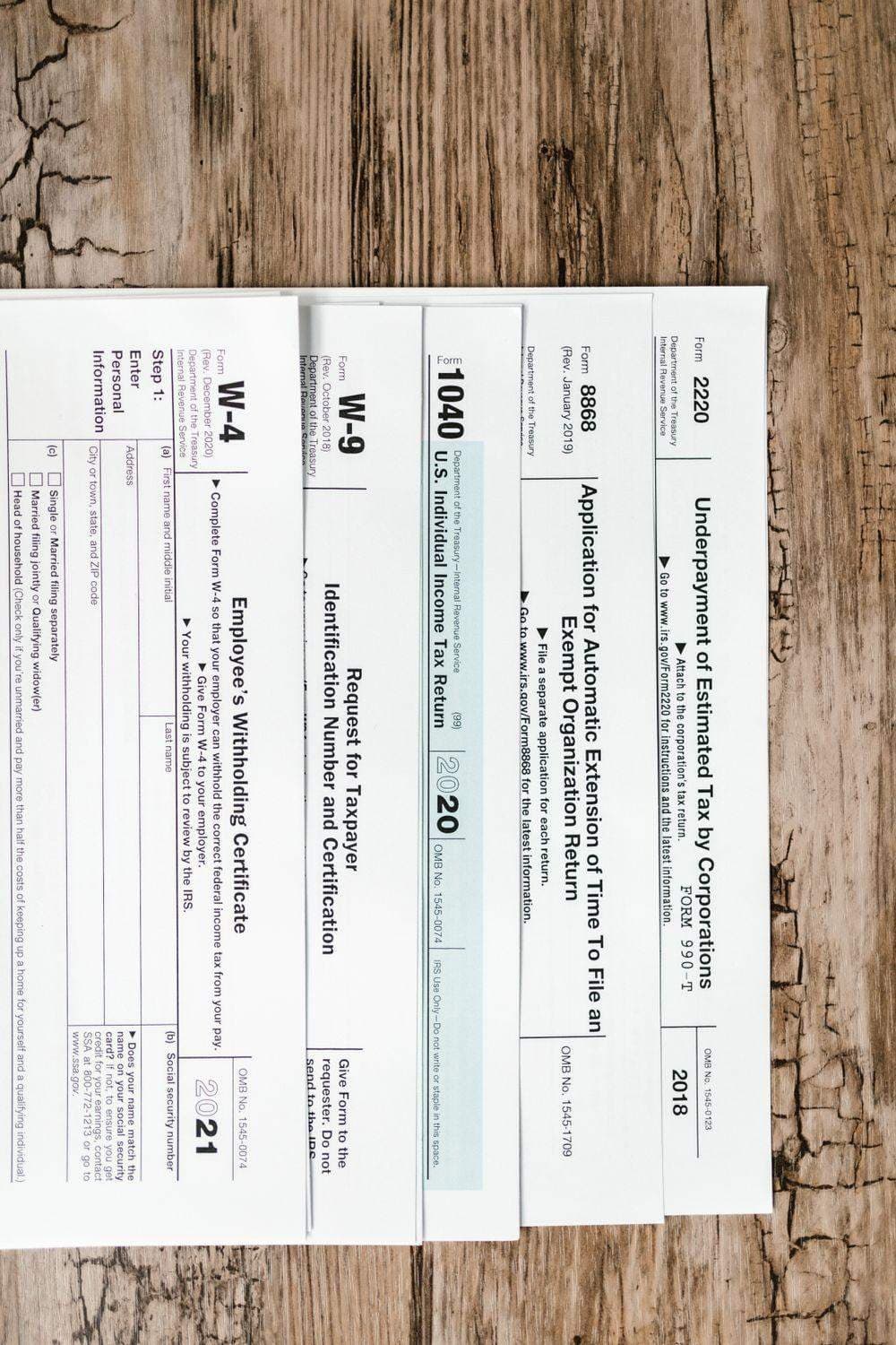 US tax forms including a W-4 laid out on a wooden table