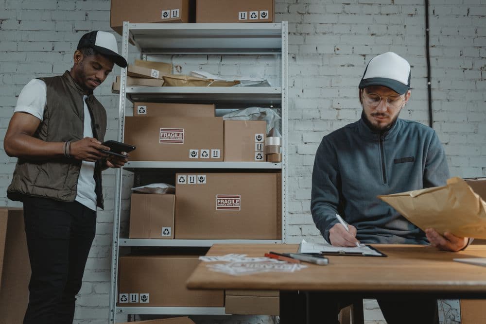 Two warehouse workers going through paperwork at a packing table