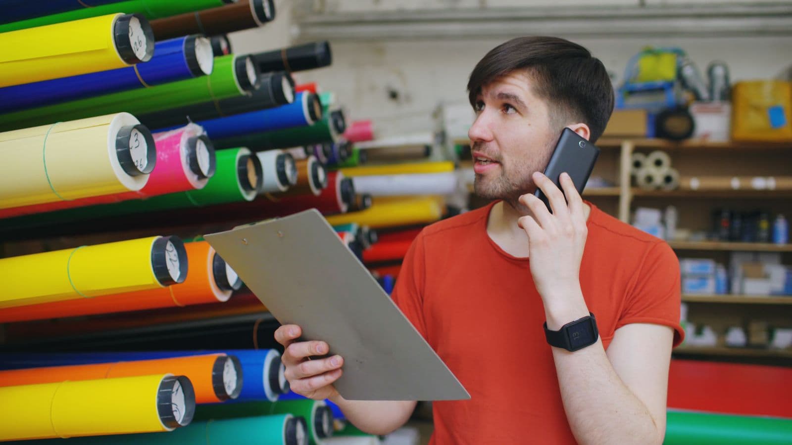 A coordinator on a phone call holding a clipboard in a stockroom