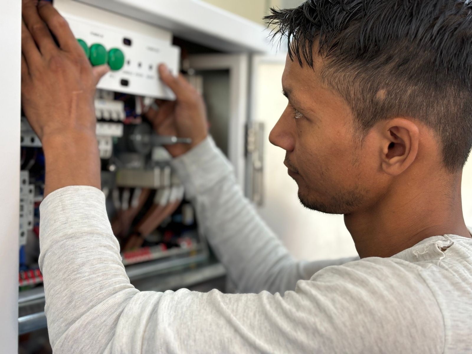 An electrician fitting a breaker into an open distribution board