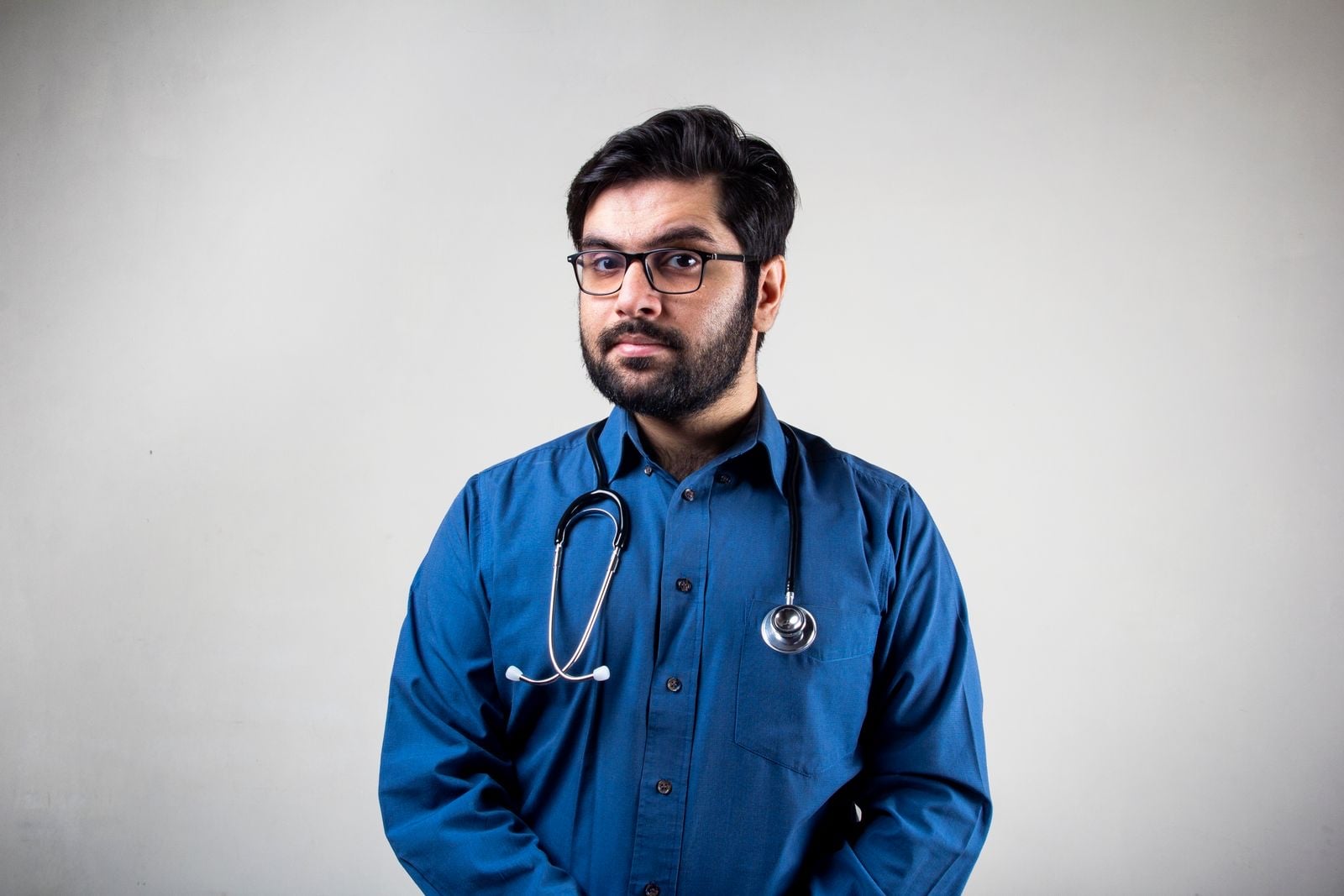 A doctor in a blue shirt with a stethoscope round his neck