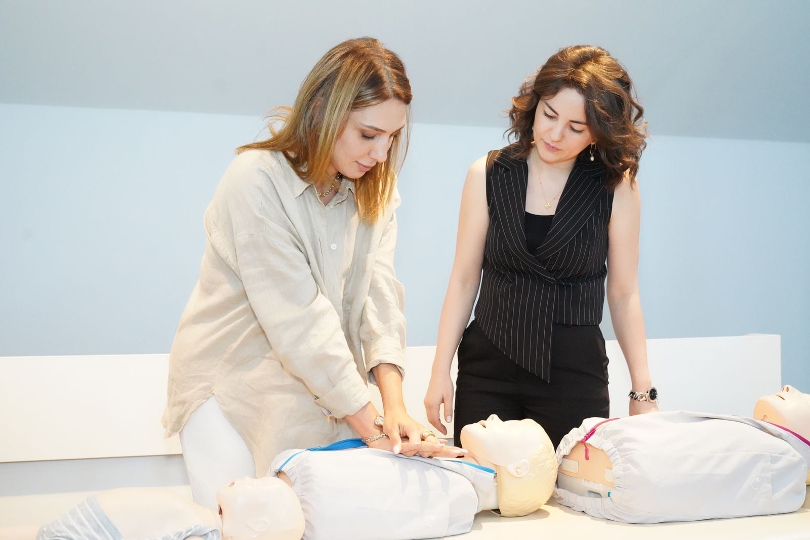 Two women practising chest compressions on training manikins