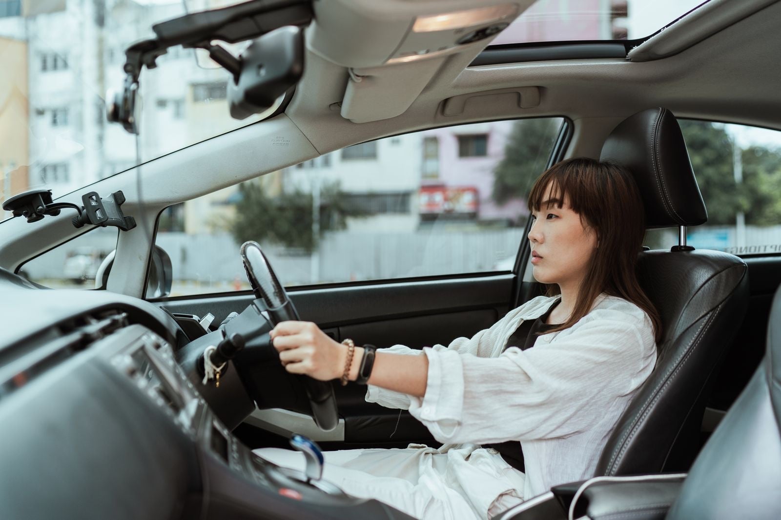 A woman at the wheel of a right-hand-drive car on a city street